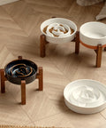 HearthFlow ceramic slow-feed bowls on acacia wood stands on a wooden floor